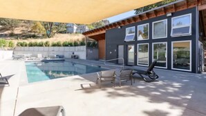A modern outdoor pool area with a pergola, lounge chairs, and a view of a hillside. - All About the View - Walk to River, Town, & Trails in Quaint Mosier (Mosier)