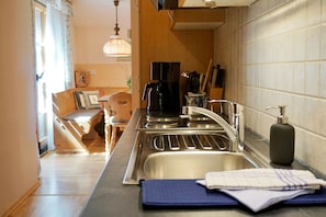 A modern kitchen with stainless steel appliances, a sink, and a dining area with wooden furniture.