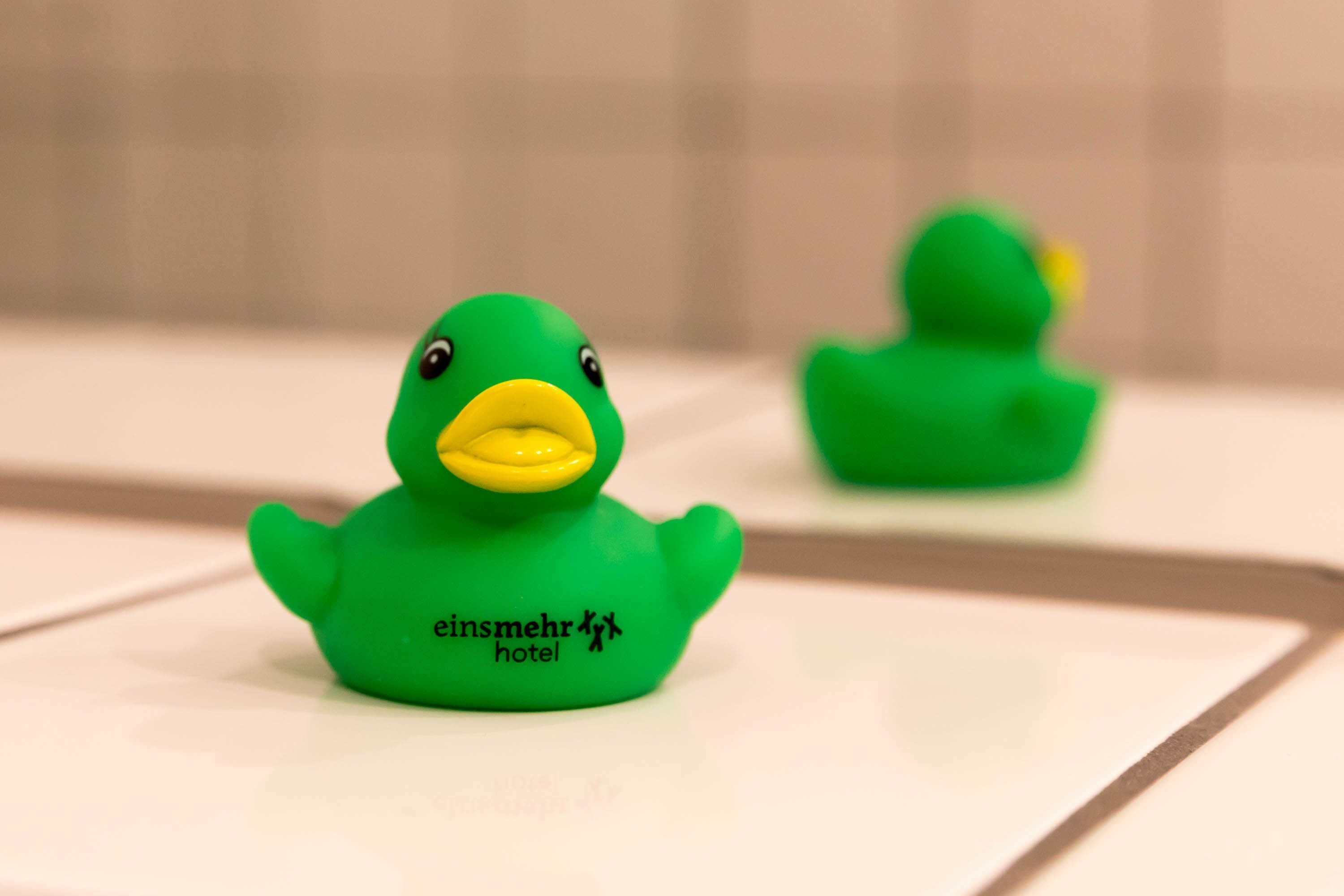 A green rubber duck with the text "einsmehr hotel" on it.
