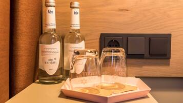 Two bottles of 'bio kristall' still wine and a glass decanter on a table with a power outlet in the background.