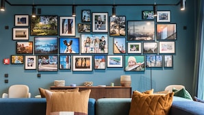 Un soggiorno con un divano blu, un tavolino da caffè con oggetti decorativi e una parete decorata con fotografie incorniciate.