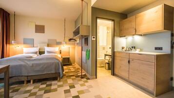 Una camera d'albergo con un letto, un comodino e un angolo cottura.