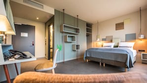 Una camera d'albergo moderna con un letto, comodini, una scrivania con telefono e una sedia.