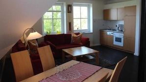 A compact living space with a dining area, a kitchenette, and a red sofa. - Villa an der Au lighthouse - Villa an der Au (Fehmarn)