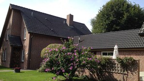 A brick house with a tiled roof, a garden with flowering bushes, and a white statue. - Villa an der Au lighthouse - Villa an der Au (Fehmarn)