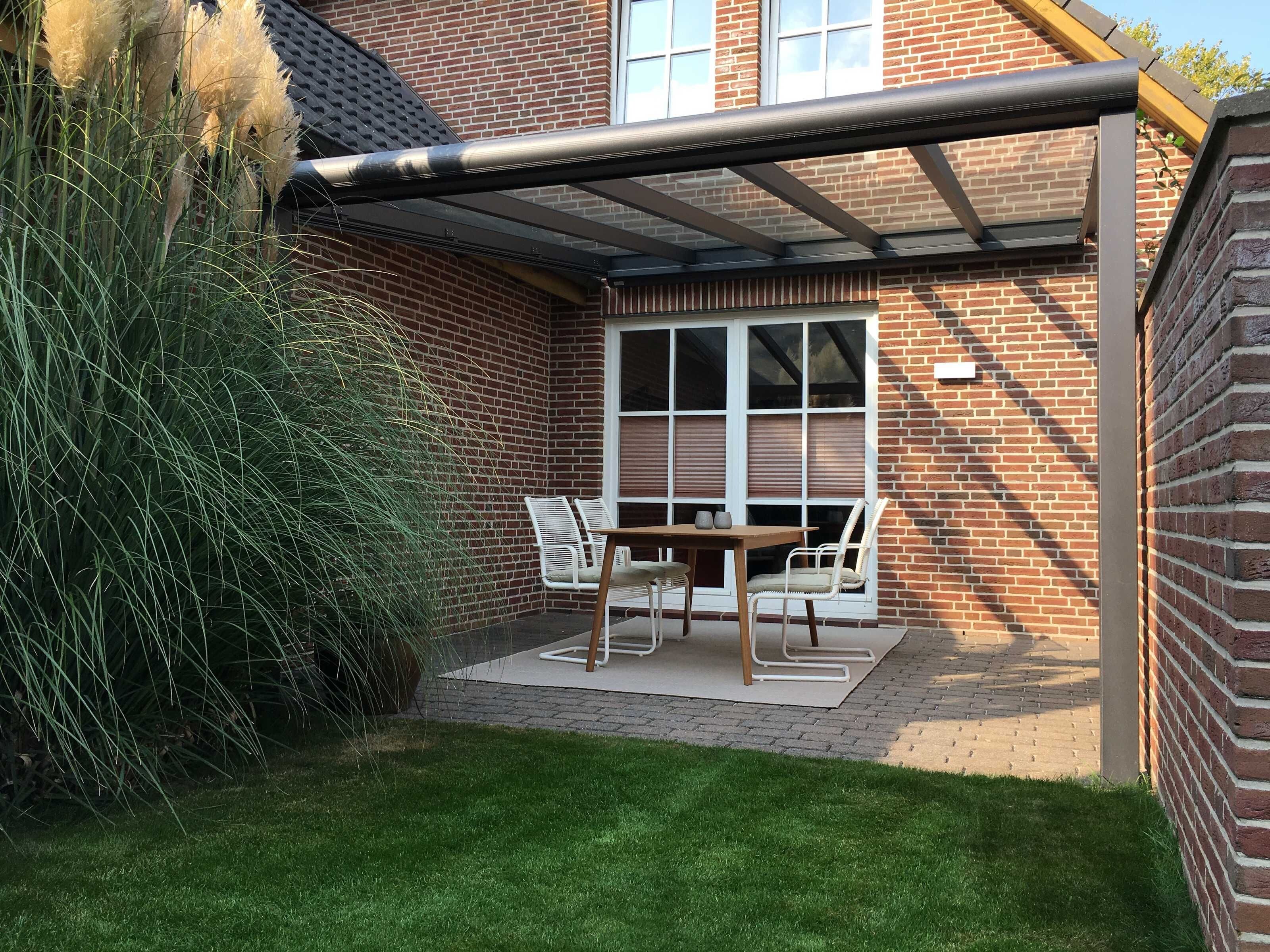A brick house with a covered patio, a table with chairs, and a window.