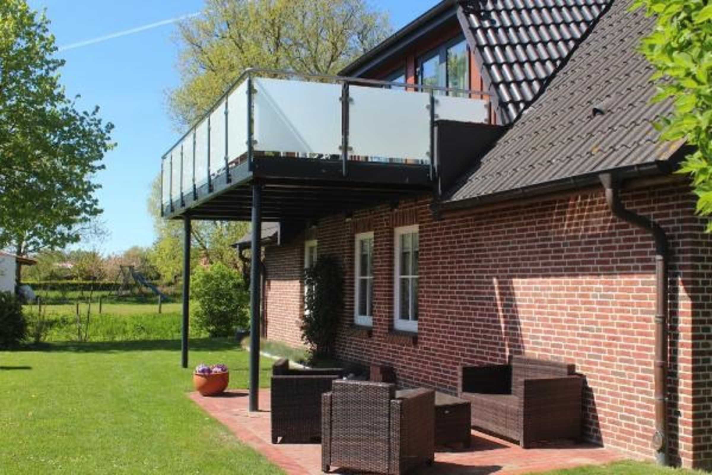Une maison en briques avec un balcon, du mobilier d’extérieur et un jardin.