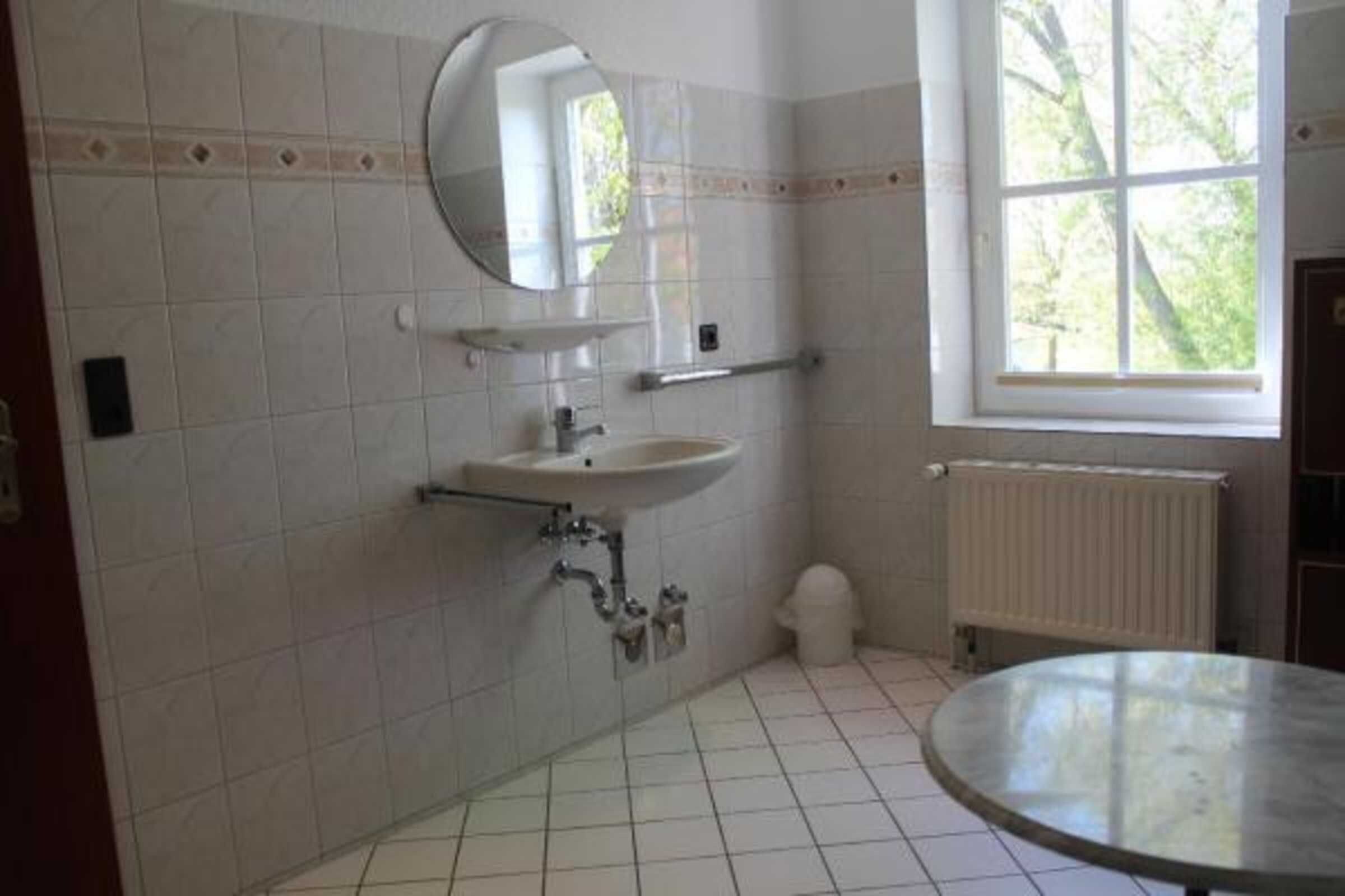 Une salle de bain avec un lavabo, un miroir et une fenêtre.