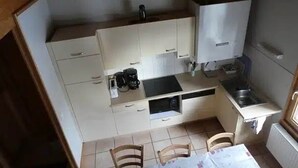 Una cocina compacta con una mesa de comedor, sillas, cafetera y refrigerador.