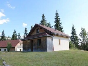 Yhden kerroksen rakennus, jossa on kalteva katto, suuri avoin autotallin ovi ja pieni erillinen varasto.