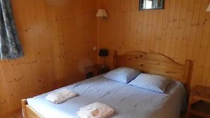 Una habitación con paneles de madera, una cama individual, una mesita de noche y una lámpara.