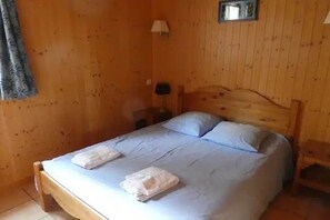 Ein Zimmer mit Holzwänden, einem Einzelbett, einem Nachttisch und einer Lampe.