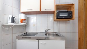 Una cocina compacta con microondas integrado, cafetera y lavamanos.