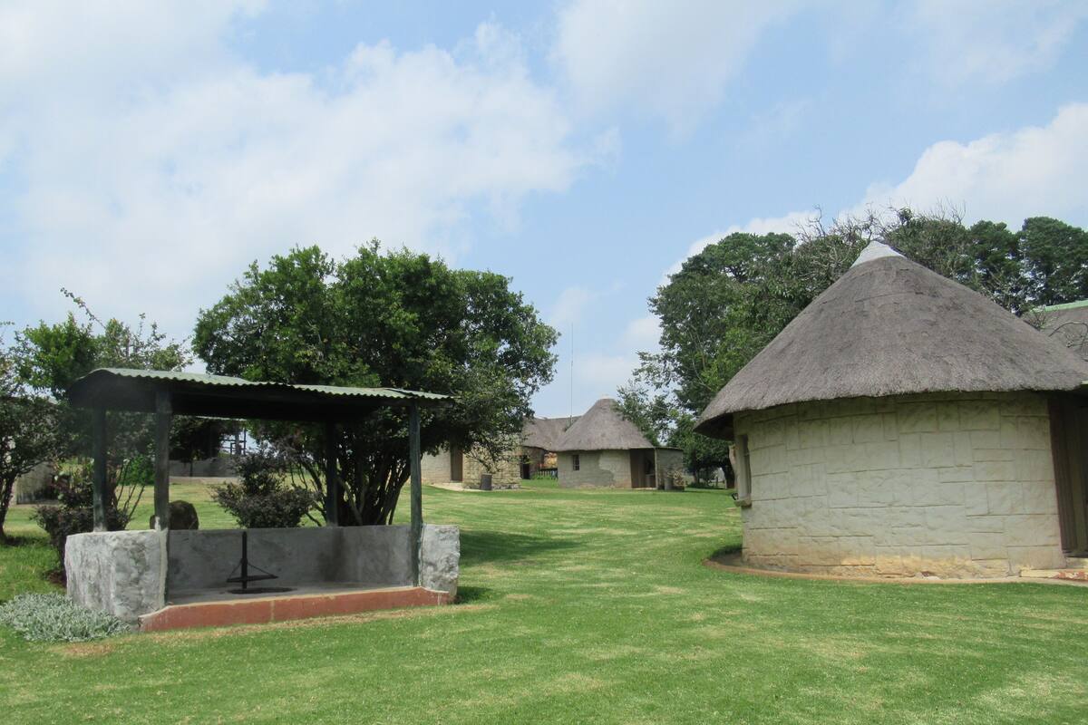 A rural setting with thatched-roof huts, a stone well, and a gazebo.