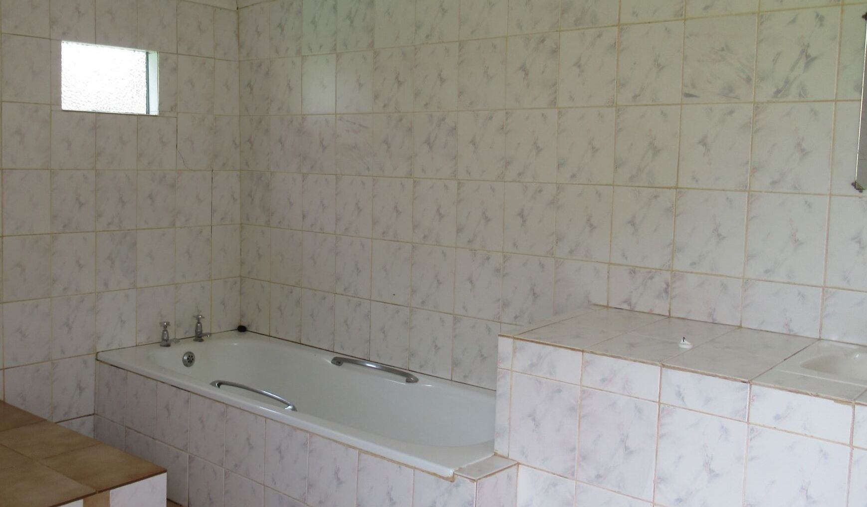 A bathroom with a bathtub, a sink, and a window.