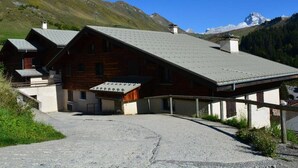Eine Holzhütte mit Satteldach, überdachter Veranda und einem Schotterweg.