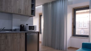 Ett modernt kök med träskåp, en mikrovågsugn och en diskmaskin. Det finns ett fönster med utsikt över en byggnad och en gardin.