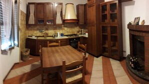 A kitchen with wooden cabinets, a dining table, chairs, a stove, and a fireplace. - HOLIDAY HOME LAKE OF SUVIANA (Bargi)