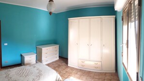 A bedroom with teal walls, a white wardrobe, a bed with a patterned bedspread, and a small bedside table. - HOLIDAY HOME LAKE OF SUVIANA (Bargi)