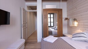 A bedroom with a bed, a TV, a wooden wall, and a hallway leading to another room.