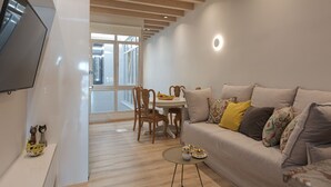 A modern living room with a sofa, a coffee table, and a dining area with chairs and a table.