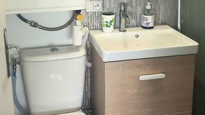 A modern bathroom with a toilet, sink, and cabinet. - Bright, functional apartment by the sea (Villers-sur-Mer)