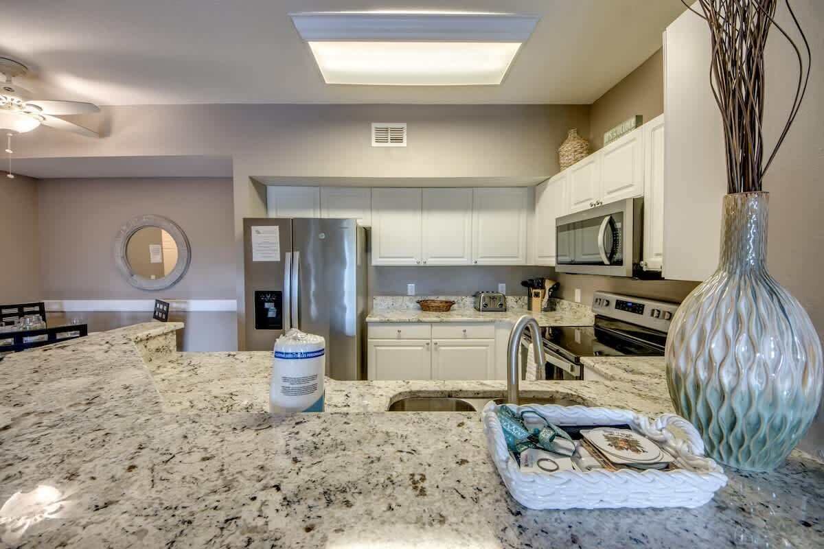A kitchen with granite countertops, stainless steel appliances, and white cabinetry.