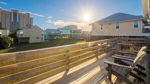 Eine Holzdar Terrasse mit Bänken, einer Rasenfläche und Gebäuden im Hintergrund.