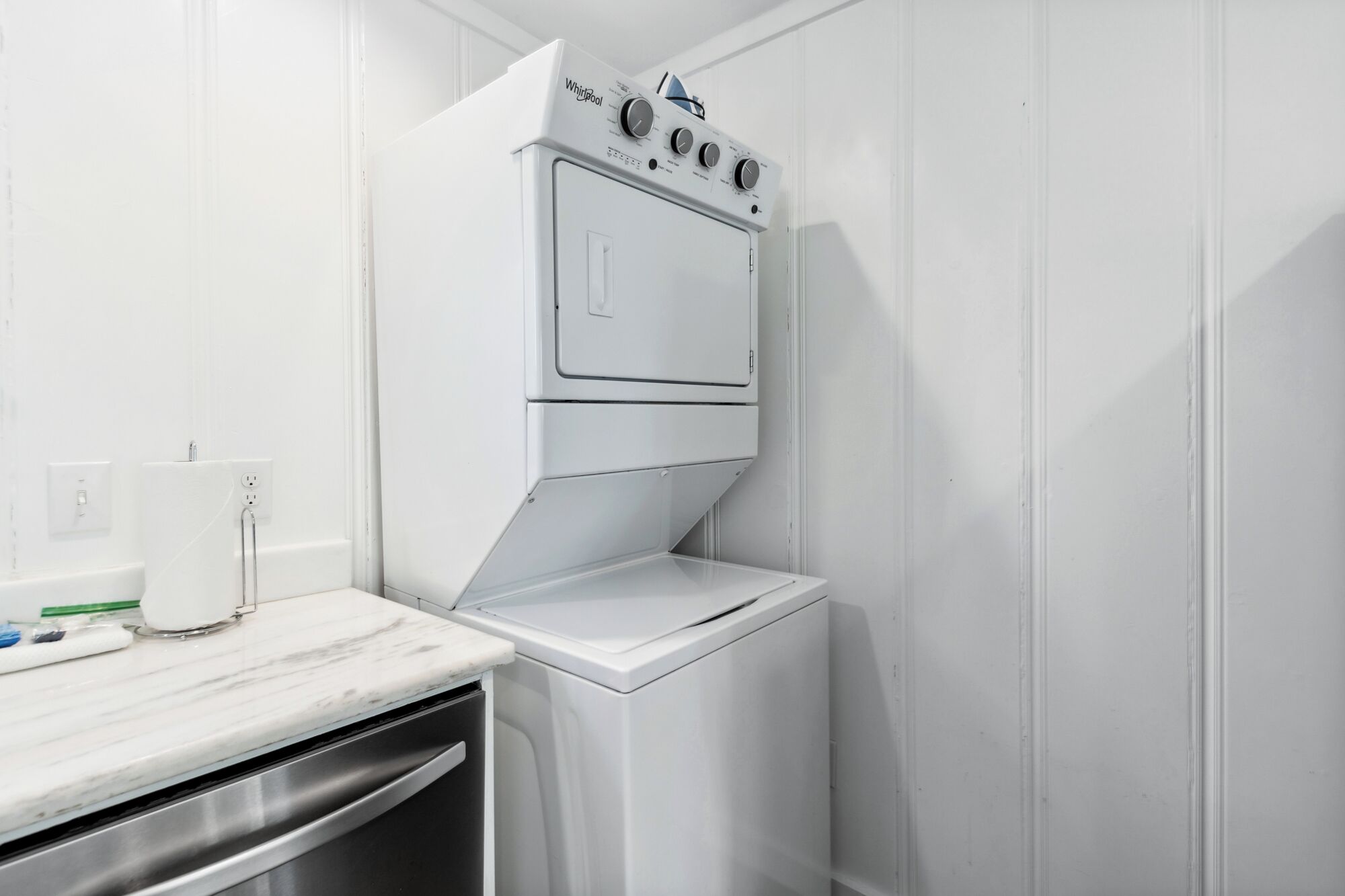 A compact laundry room with a built-in washer and dryer, a marble countertop, and a power outlet.