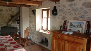 Une pièce rustique avec une table en bois, un banc, une cheminée, une fenêtre et un buffet en bois.