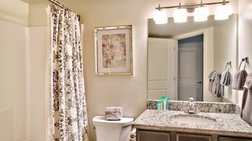 Une salle de bain équipée d’un rideau de douche, de toilettes, d’un lavabo, d’un miroir et d’un porte-serviettes.