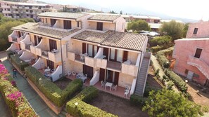 Un edificio de varios pisos con balcones, mobiliario exterior y un jardín.
