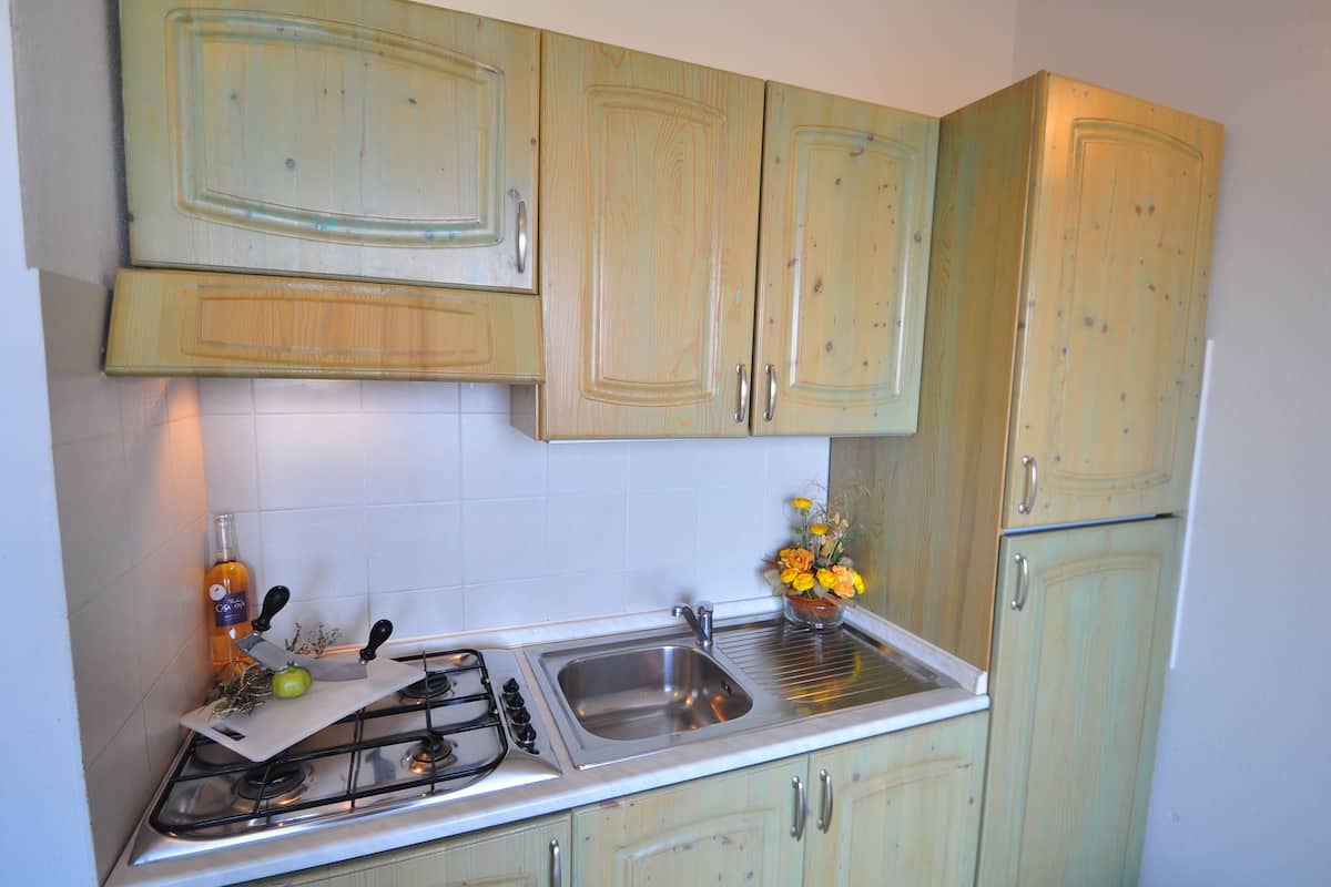 A kitchen with a gas stove, sink, and light green cabinets.