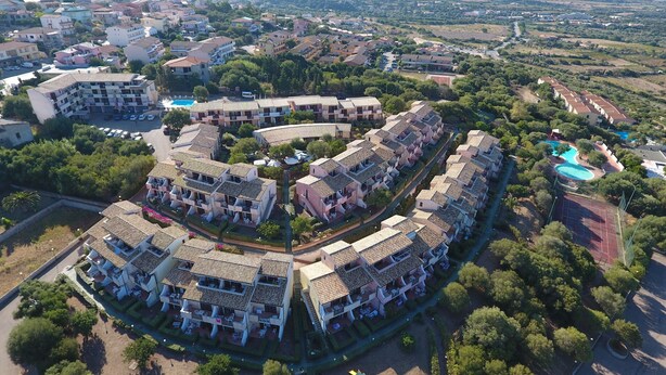 An aerial view of a residential area with multiple apartment buildings, a swimming pool, and well-maintained gardens. - Residenze La Corte (Badesi)