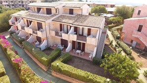 A multi-story residential building with balconies, outdoor seating, and a garden area. - Residenze La Corte (Badesi)