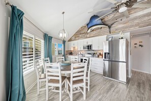 A modern kitchen with white cabinets, stainless steel appliances, and a dining area with white chairs.