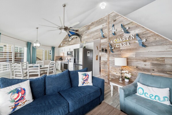Una sala de estar moderna con un sofá azul, un comedor y una cocina.