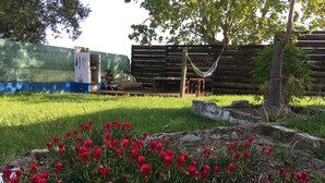 Un jardin avec des tulipes rouges, un hamac et une clôture en bois.