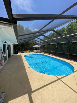 Una piscina coperta con area protetta, una sedia a bordo vasca e vista sull'esterno.