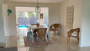 A spacious living room with a dining area, a pool visible through the glass door, and a large wall tapestry. - 3 bedroom, 2 bathroom private pool home just minutes from Siesta Key! (Sarasota)