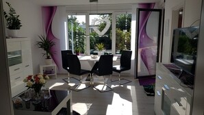 A modern dining area with a table and chairs, a TV, and a view of the outdoors.