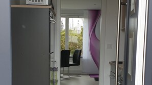A modern interior with a kitchen area, a dining space, and a view through a doorway.