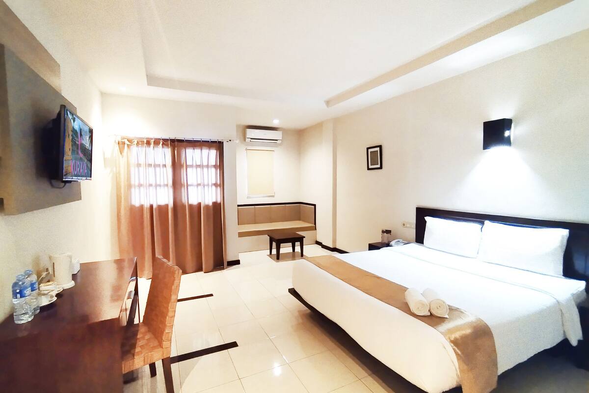 Une chambre d’hôtel équipée d’un lit, d’un bureau, d’une chaise, d’une télévision et d’un appareil de climatisation.