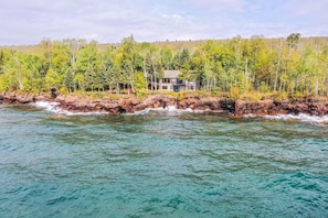 A coastal property with a house on a rocky shoreline, surrounded by dense forest.