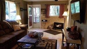 A cozy living room with a fireplace, a sofa, a coffee table, and a rug.