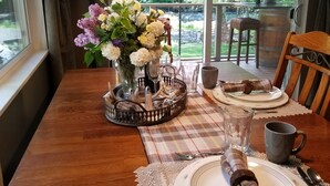 A dining table set with a vase of flowers, plates, cutlery, and a candle.