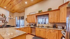A spacious kitchen with wooden cabinets, granite countertops, and a built-in dishwasher. - Huge Cabin Near Woodland Lake, Sleeps 36! (Pinetop-Lakeside)