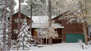 A wooden cabin with a green garage door, surrounded by snow-covered trees. - Huge Cabin Near Woodland Lake, Sleeps 36! (Pinetop-Lakeside)