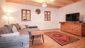 Un salon confortable avec un canapé, une table basse, un téléviseur et un meuble en bois.