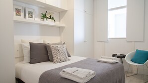 Een moderne hotelkamer met een netjes opgemaakt bed, een tafeltje met een stoel en een raam dat natuurlijk licht binnenlaat.